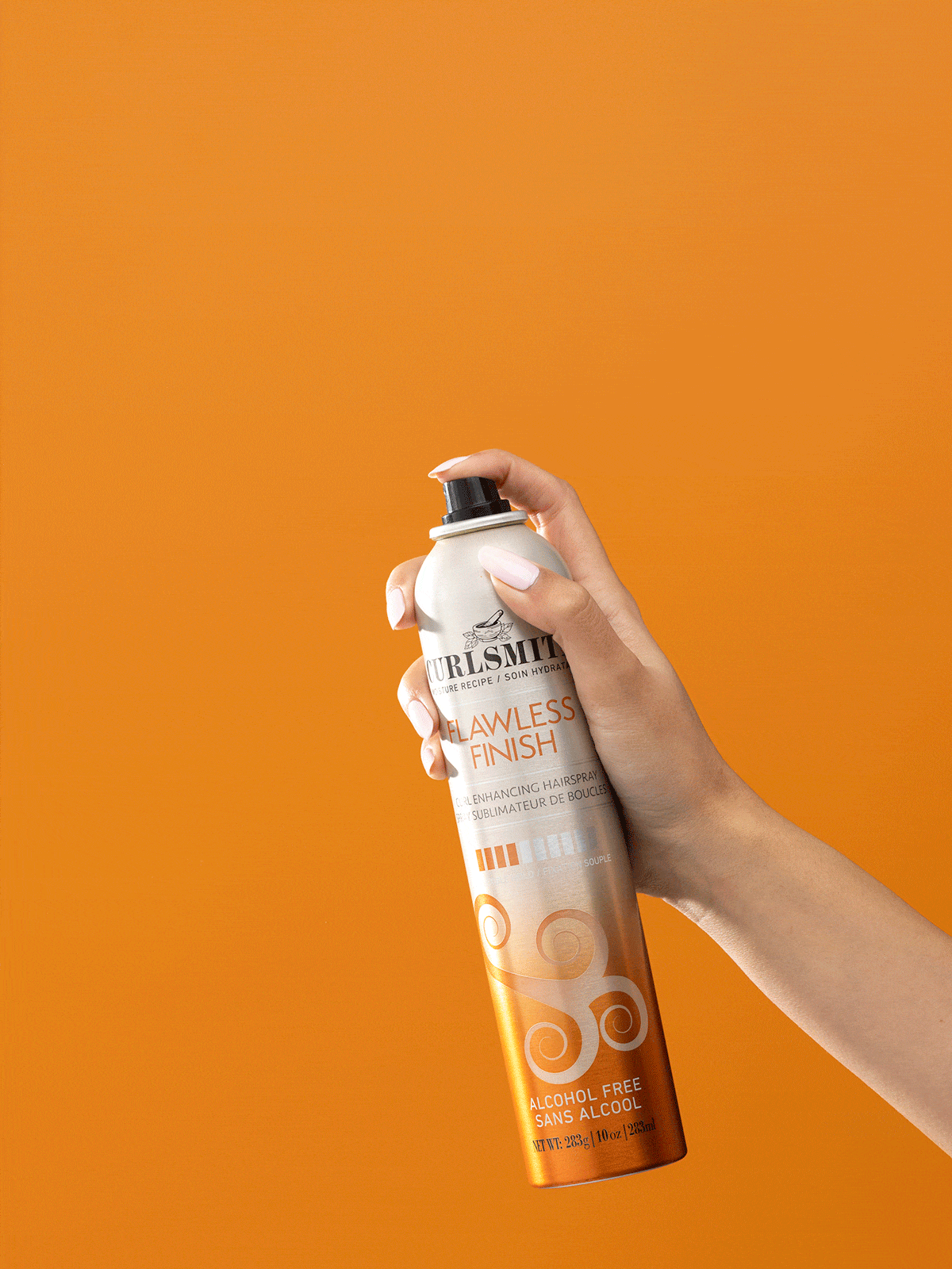 Hand spraying Curlsmith Flawless Finish hair product on an orange background