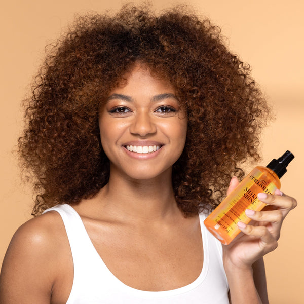 Woman holding a bottle of hair care product against a beige background