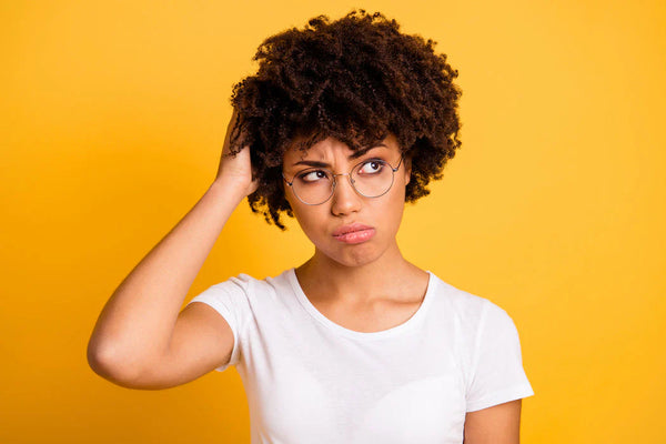 Woman with curly hair and glasses against a yellow background