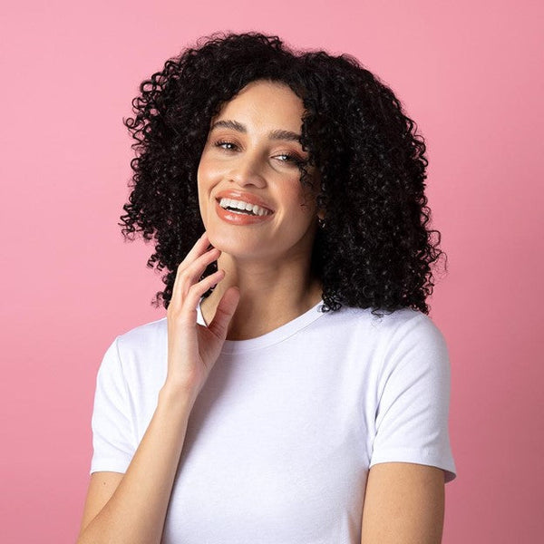 Curly woman in front of pink background