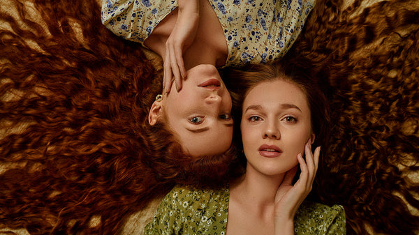 Two women with curls laying on the floor with hair spread out