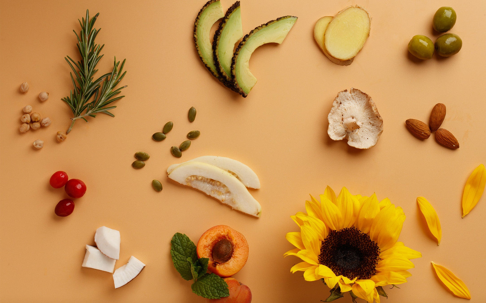 Various fruits, vegetables, and a sunflower arranged on a beige background